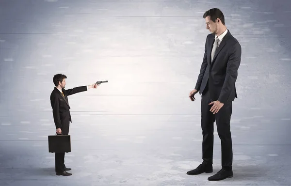 Small businessman shooting giant businessman — Stock Photo, Image