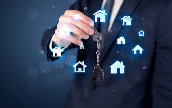 Empresário segurando chaves com casas ao redor — Fotografia de Stock