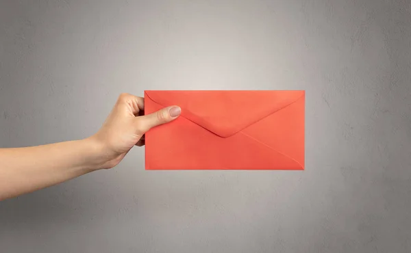 Hand holding envelope with empty wall background — Stock Photo, Image