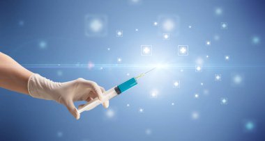 Kadın doktor elinde şırınga tutuyor.