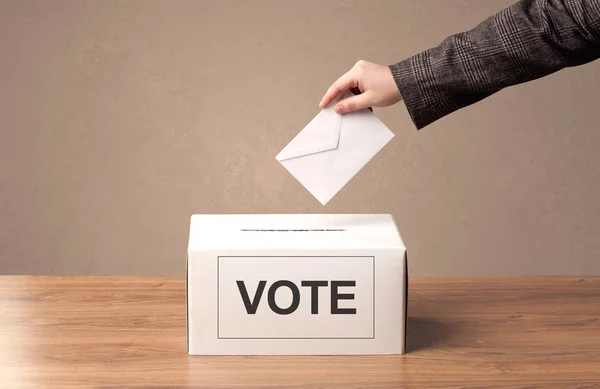 Fechar a mão masculina colocando voto em uma urna — Fotografia de Stock