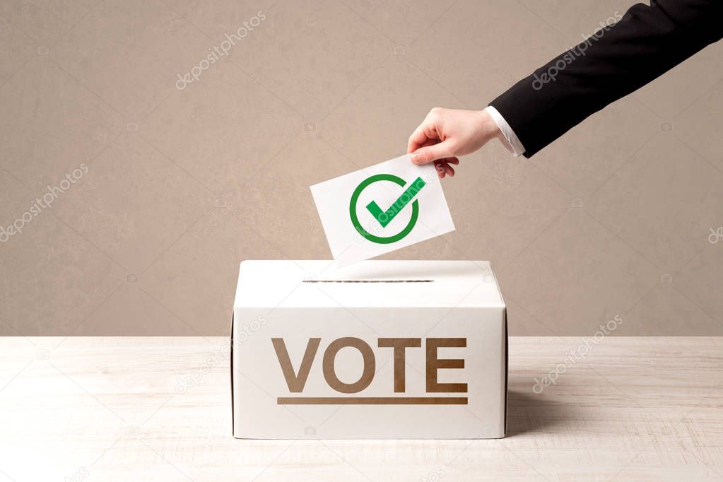 Close up of male hand putting vote into a ballot box