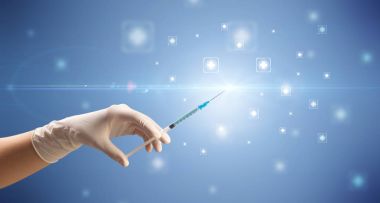 Kadın doktor elinde şırınga tutuyor.