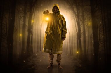 Mysterious man coming from a path in the forest with glowing lantern concept clipart