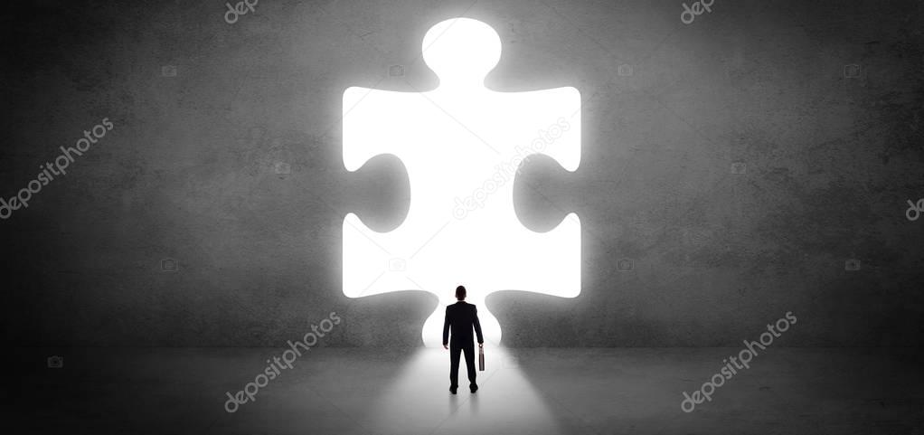 Businessman standing in front of a big puzzle piece