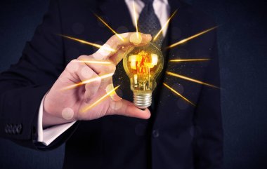 bir elektrik ampulü tutan iş kişi