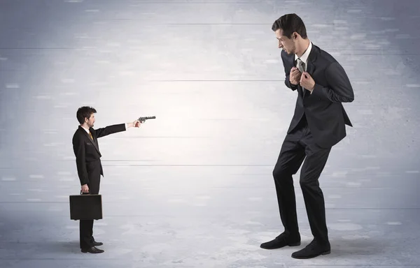 Small businessman shooting giant businessman — Stock Photo, Image