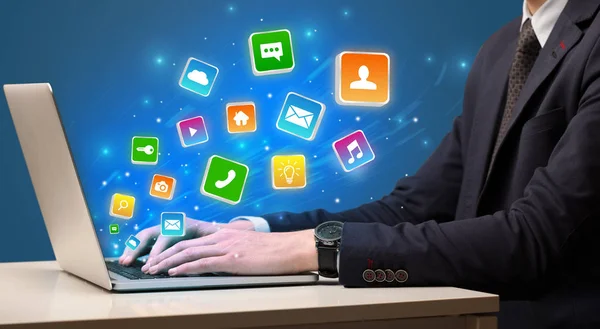 Hand mit Laptop mit herumfliegenden Anwendungssymbolen — Stockfoto