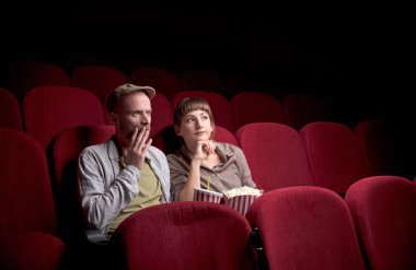 Genç çift kırmızı sinemada oturuyor
