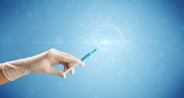 Kadın doktor elinde şırınga tutuyor.