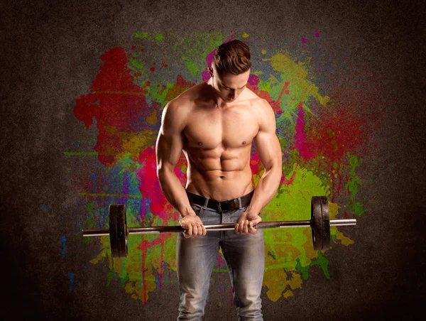 Strong guy with colorful paint wall and weight — Stock Photo, Image