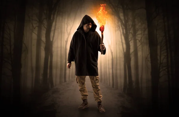 Man coming from dark forest with burning flambeau in his hand concept — Stock Photo, Image