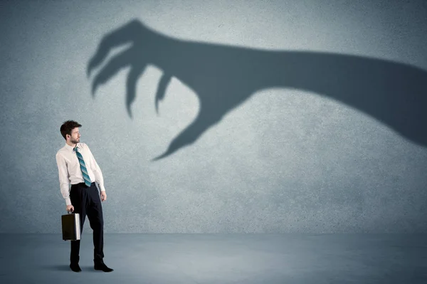Persona de negocios con miedo de un gran concepto de sombra de garra monstruo — Foto de Stock