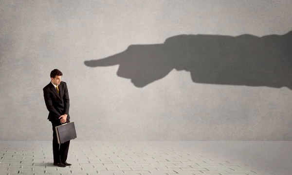 Business person looking at huge shadow hand pointing at him concept — Stock Photo, Image