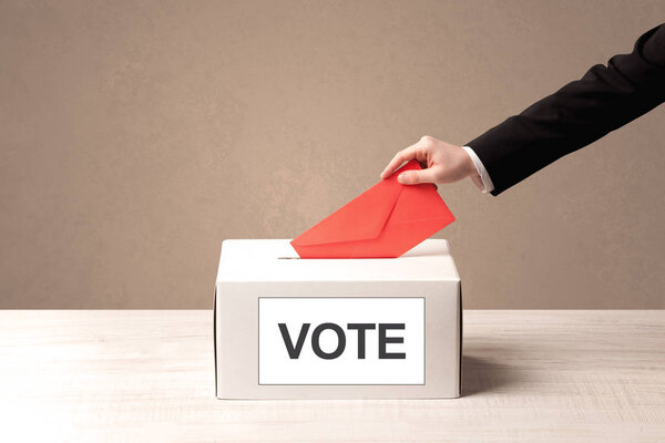 Крупный план мужской руки, помещающей голоса в урну для голосования
