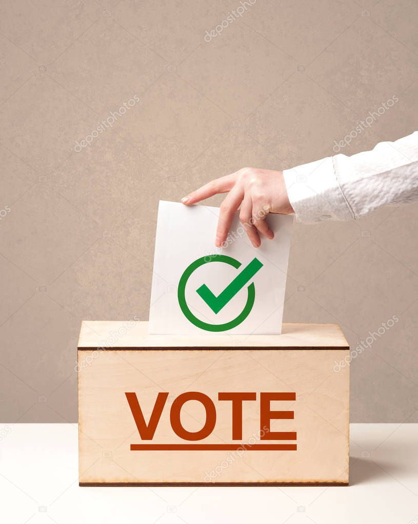 Close up of male hand putting vote into a ballot box