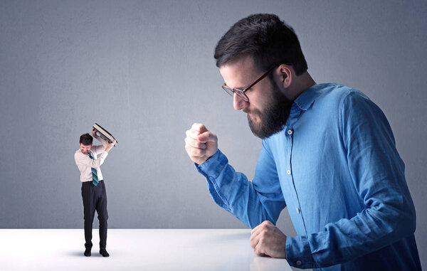 Young businessman fighting with miniature businessman