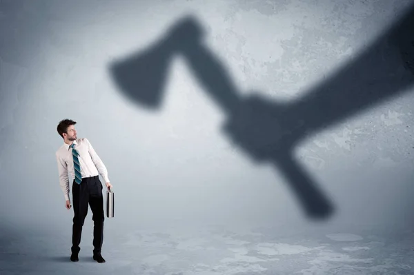 Businessman afraid of a huge shadow hand holding an axe concept — Stock Photo, Image