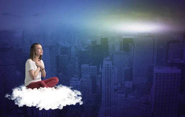 Жінка сидить на хмарі над містом — стокове фото