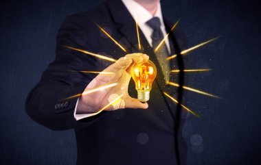 bir elektrik ampulü tutan iş kişi