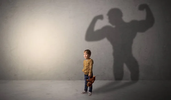 Muscleman árnyék mögött huncut kisfiú — Stock Fotó