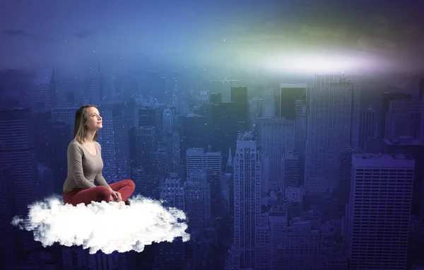 Vrouw zitten op wolk boven de stad — Stockfoto