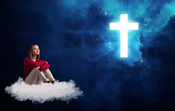 Kobieta siedzi na chmurze patrząc na krzyż — Zdjęcie stockowe