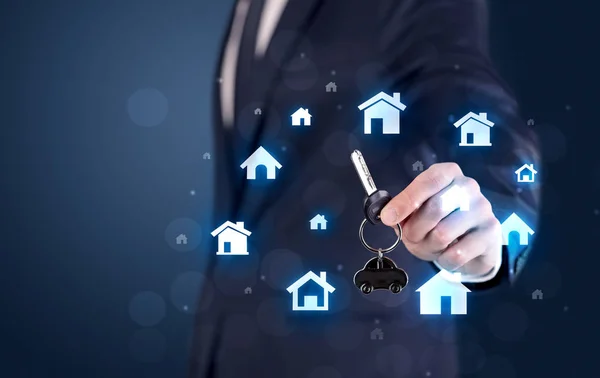 Businessman holding keys with houses around — Stock Photo, Image