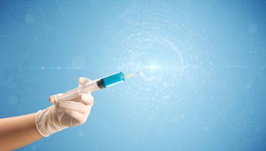 Kadın doktor elinde şırınga tutuyor.