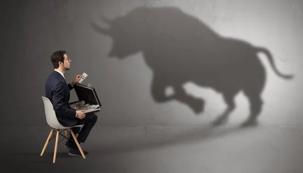 Businessman staying and offering stuffs to a huge bull shadow — Stock Photo, Image