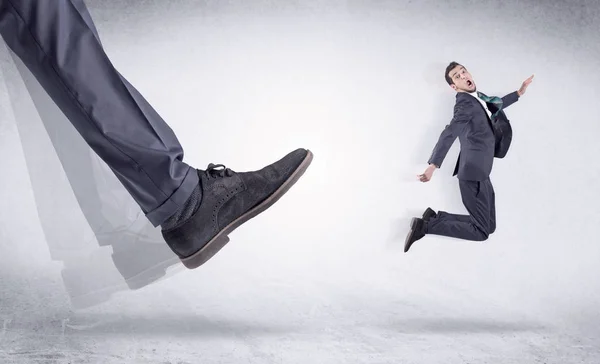 Sapato preto chutando homem pequeno — Fotografia de Stock