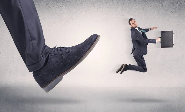 Small businessman kicked by big shoe — Stock Photo, Image