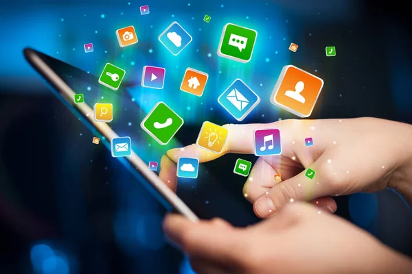 Main en utilisant une tablette avec des icônes d'application volant autour — Photo
