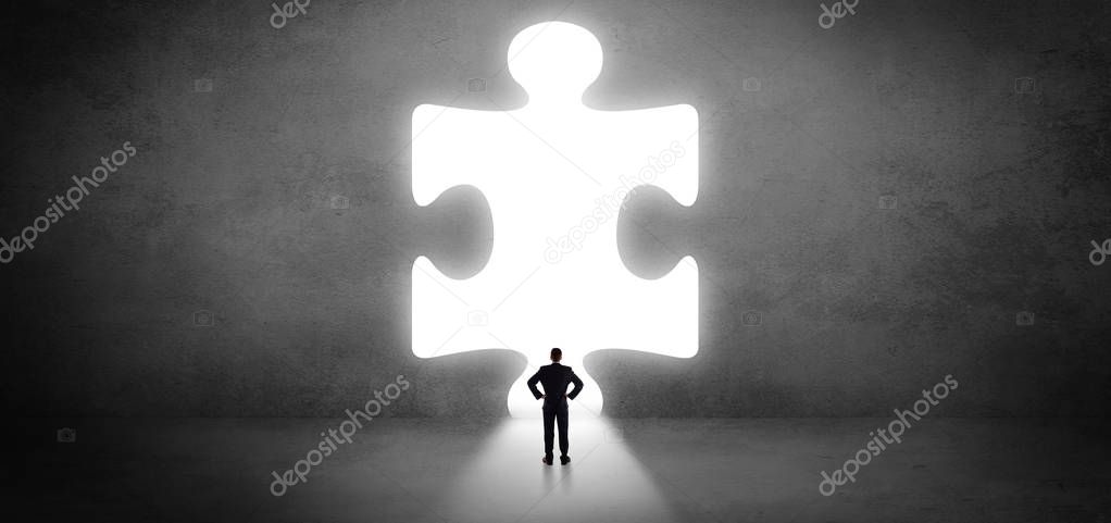 Businessman standing in front of a big puzzle piece