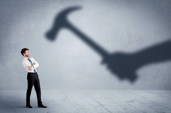 Business person afraid of a shadow hand holding hammer concept — Stock Photo, Image