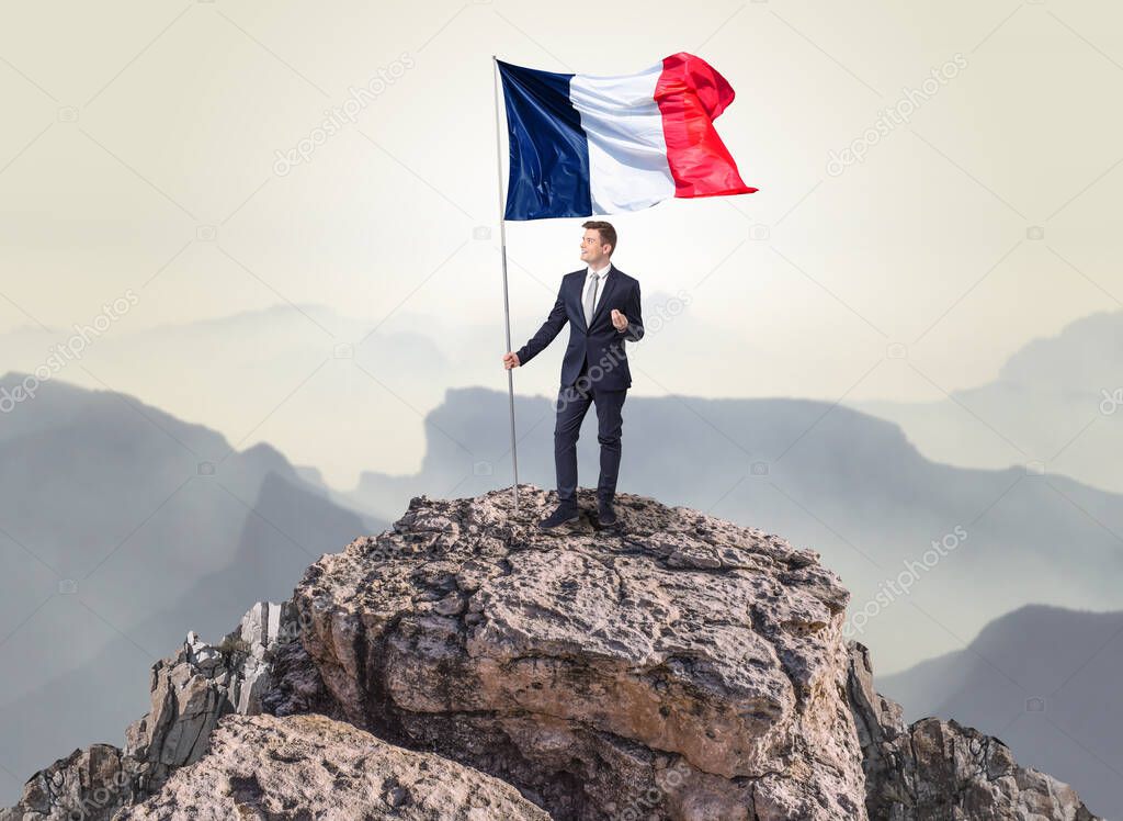 Businessman on the top of a rock holding flag