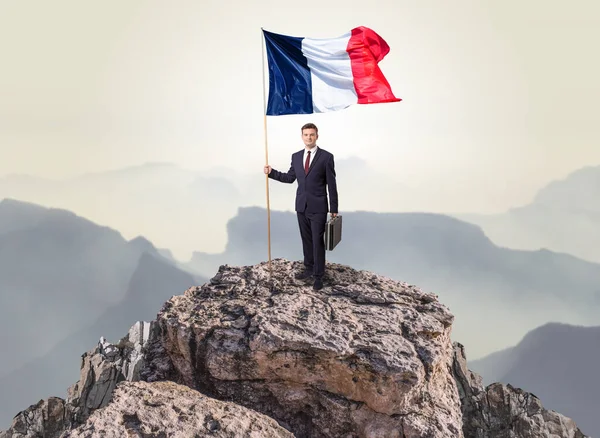 Businessman on the top of a rock holding flag — Stock Photo, Image