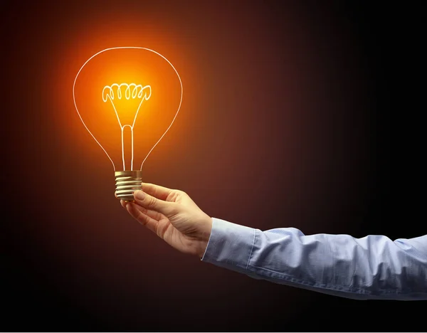 Hand holding light bulb on dark background — Stock Photo, Image