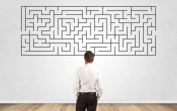 Geschäftsmann blickt auf ein Labyrinth an einer Wand — Stockfoto