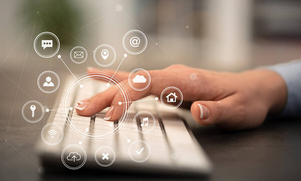 Hand typing on keyboard with application icons around