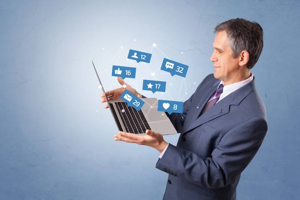 Hombre sosteniendo portátil con notificaciones de redes sociales —  Fotos de Stock
