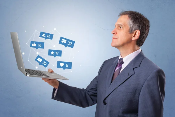 Hombre sosteniendo portátil con notificaciones de redes sociales —  Fotos de Stock