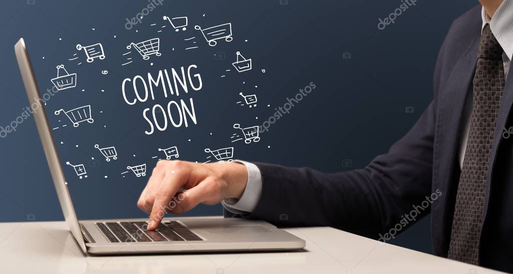 Businessman working on laptop with COMING SOON inscription, online shopping concept