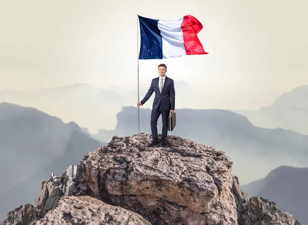 Empresário no topo de uma bandeira de rocha — Fotografia de Stock