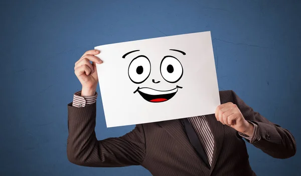 Estudiante sosteniendo un papel con emoticono riéndose delante de su cara — Foto de Stock