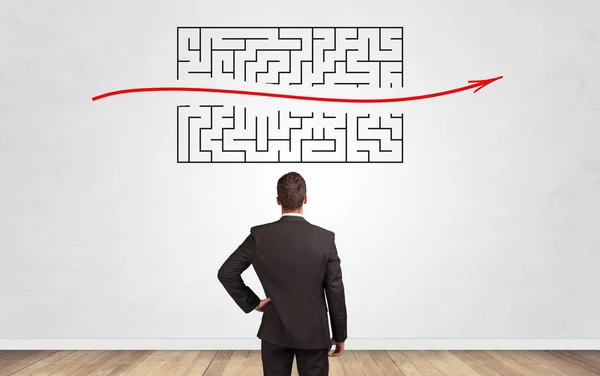 Businessman looking to a maze on a wall — Stock Photo, Image