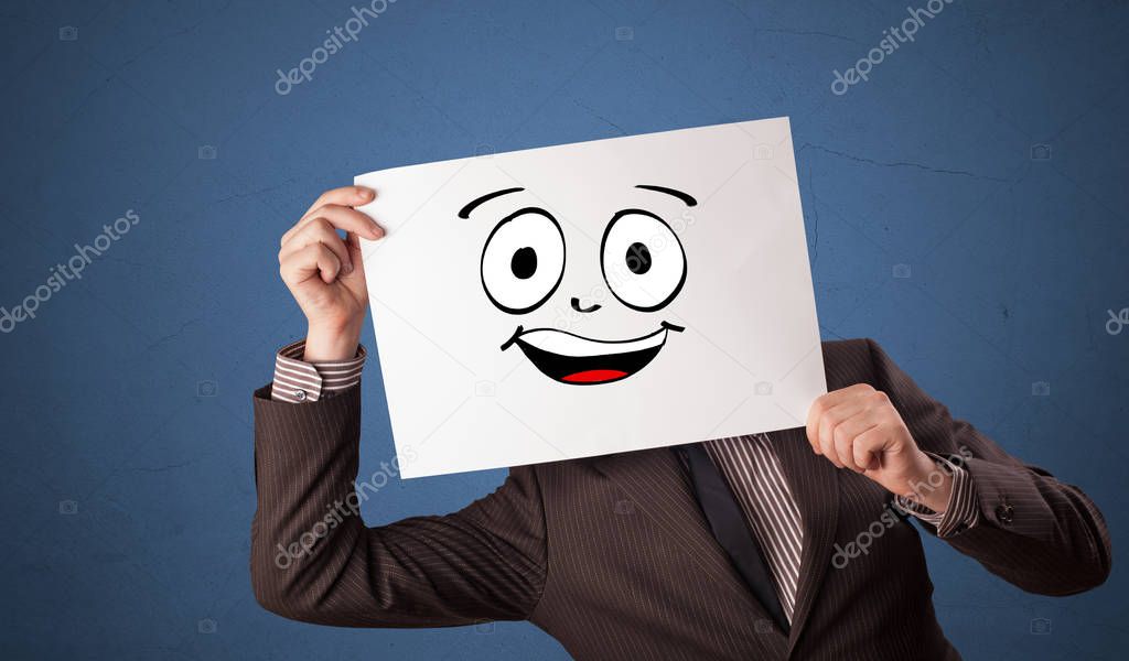 Student holding a paper with laughing emoticon in front of his face