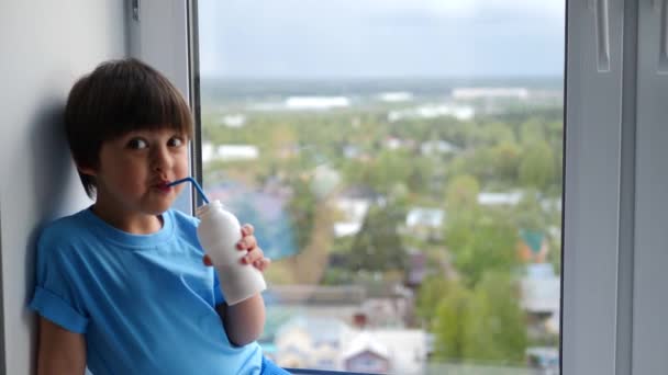 Child boy in a blue T-shirt sits on the window of a high floor — Stock Footage Child boy in a blue T-shirt sits on the window of a high floor Royalty Free Stock Video