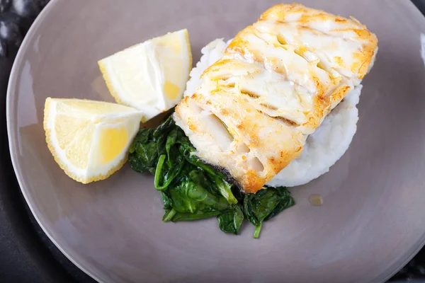 Filetes de bacalhau fritos e espinafre na placa — Fotografia de Stock