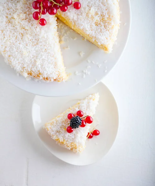 Um pedaço de bolo de coco caseiro em um prato branco — Fotografia de Stock
